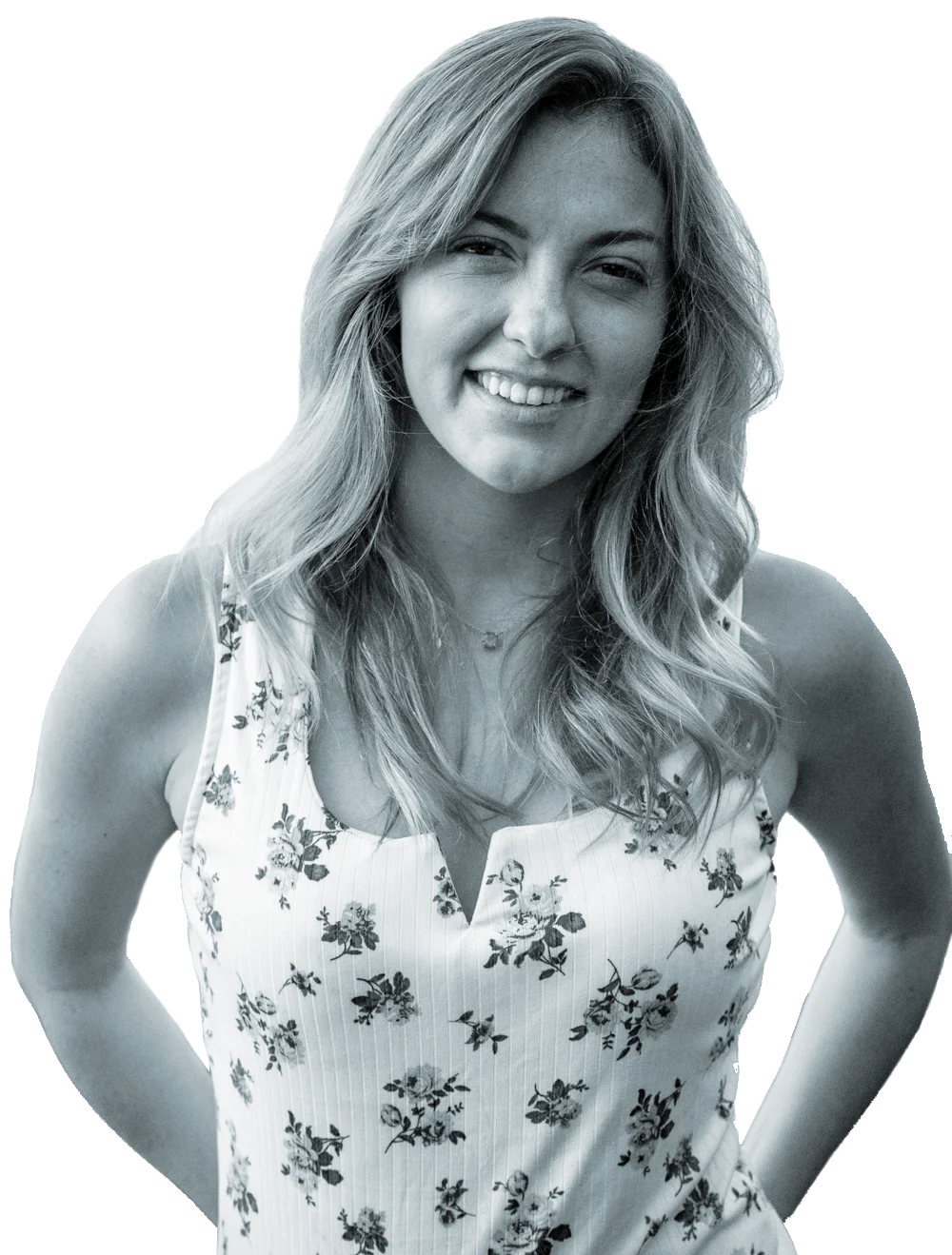A smiling woman with wavy, shoulder-length hair, wearing a sleeveless floral top and a necklace.