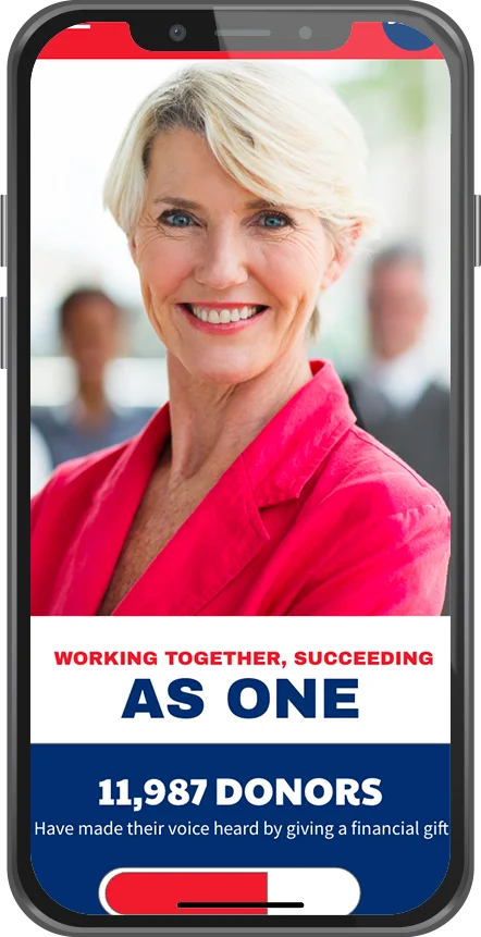 A woman with short blonde hair, wearing a pink blazer, smiling at the camera in a professional setting, with blurred people in the background.